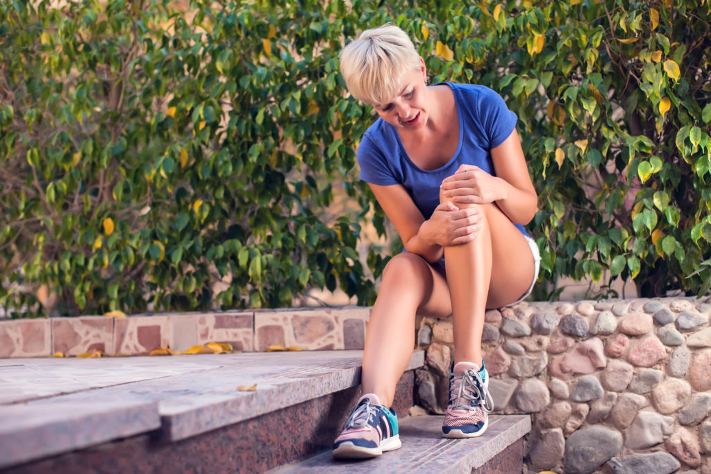 Woman feeling knee pain while doing exercises